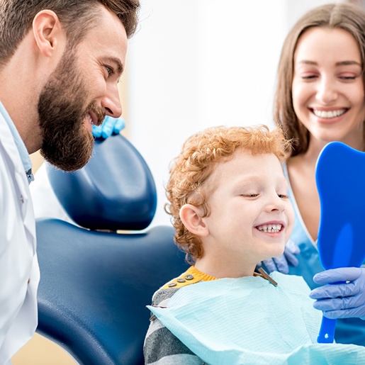 Child smiling in mirror after dental cleaning