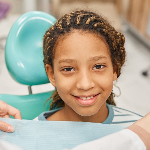 young girl smiling while sitting in treatment chair 