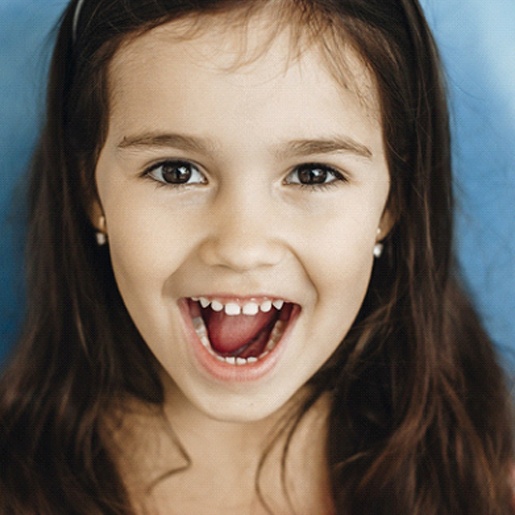 A little girl with long, dark hair smiling with her mouth open after seeing her dentist near Aledo, TX